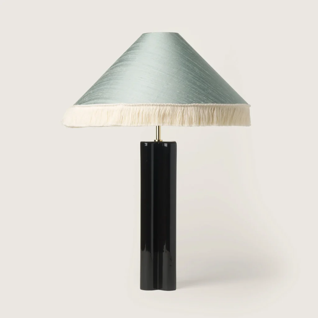 Elegant table lamp with a shade, white fringe, and a black base.