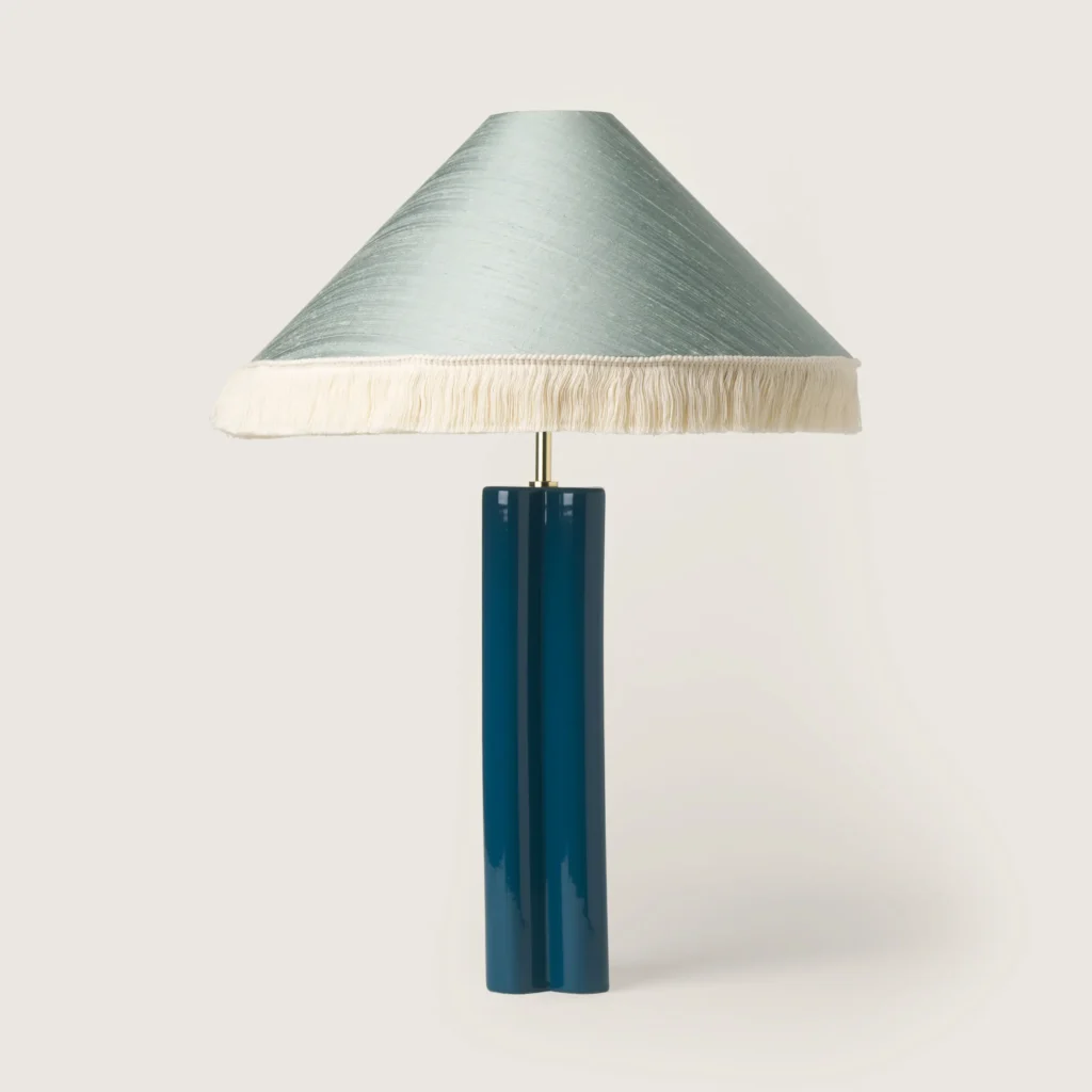 Elegant table lamp with a shade, white fringe, and a blue base.