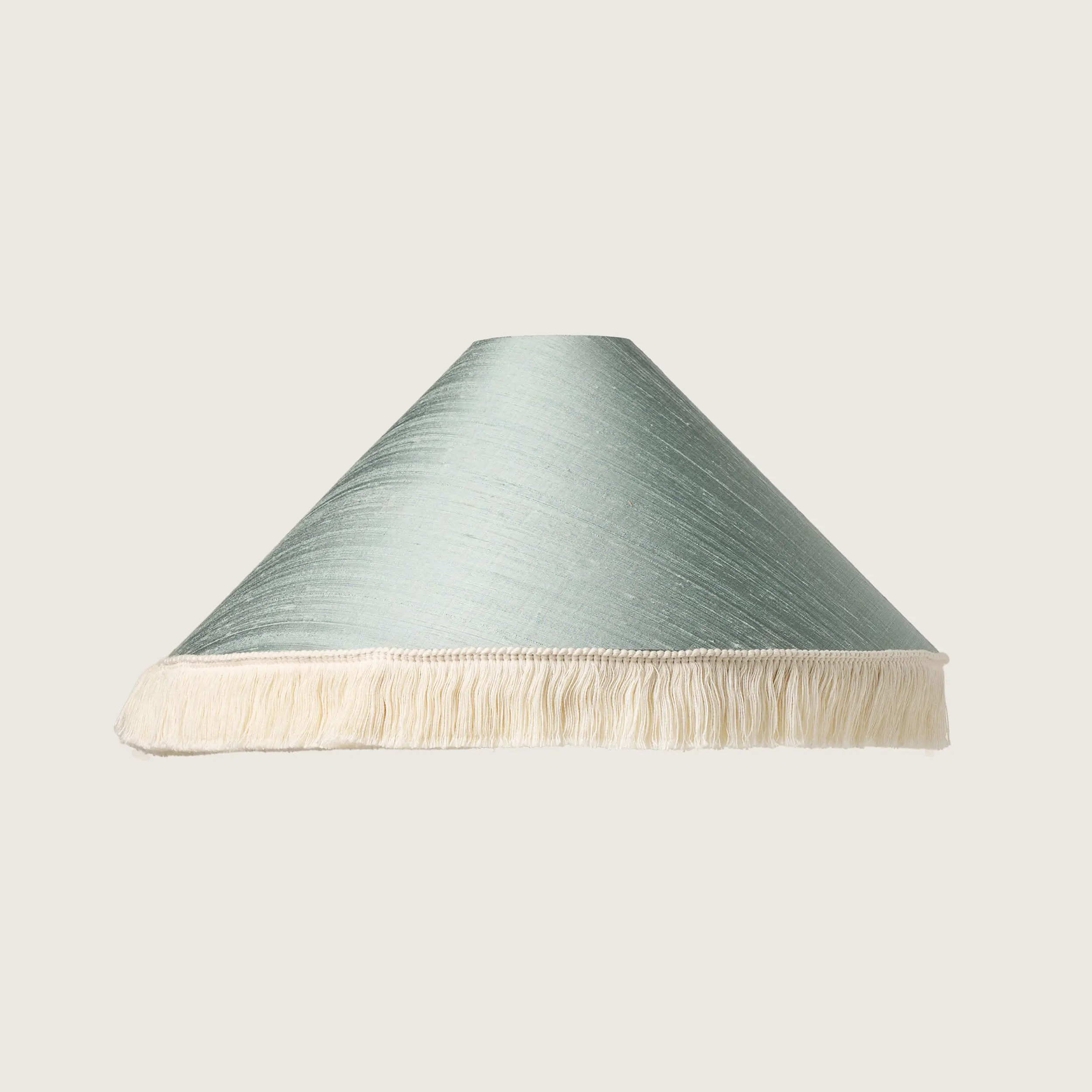A beautifully formed conical lampshade, finished with a delicate white fringe along the bottom edge.
