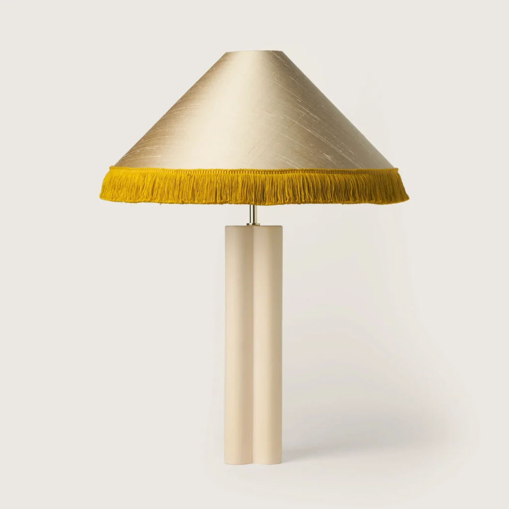 Elegant table lamp with a shade, yellow fringe, and a cream base.