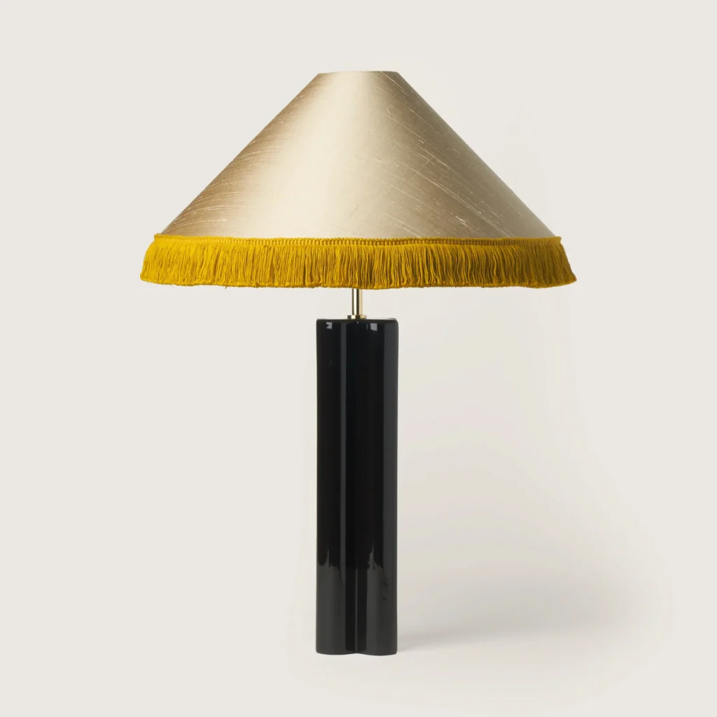 Elegant table lamp with a shade, yellow fringe, and a black base.