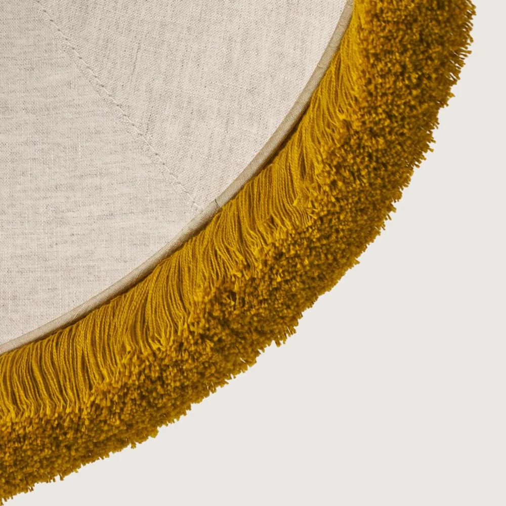 A close-up of the beautifully formed cone-shaped lampshade, finished with a delicate yellow fringe along the bottom edge.