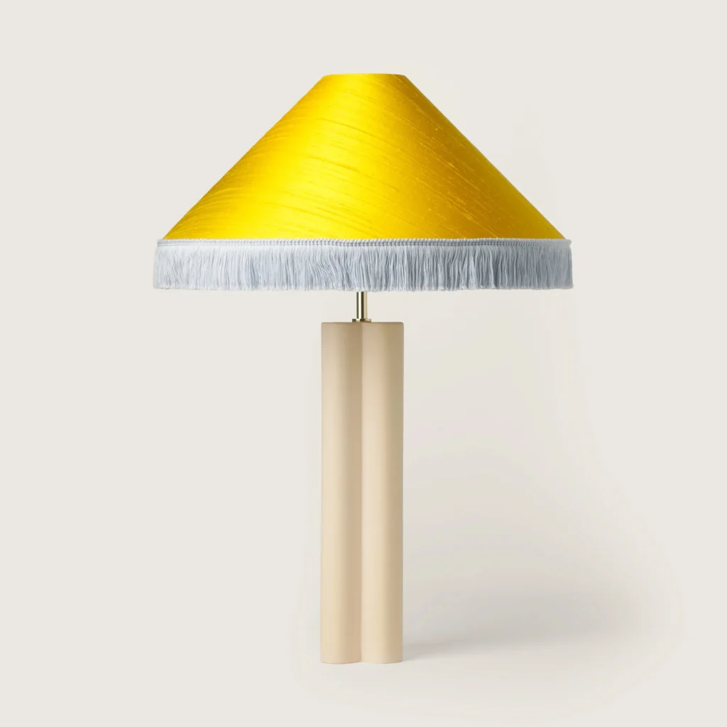 Elegant table lamp with a yellow shade, white fringe, and a cream base.