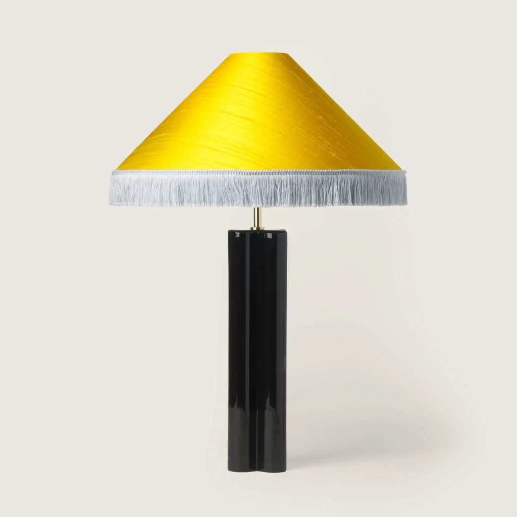 Elegant table lamp with a yellow shade, white fringe, and a black base.