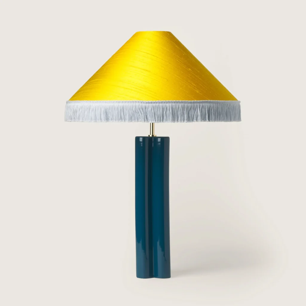 Elegant table lamp with a yellow shade, white fringe, and a blue base.