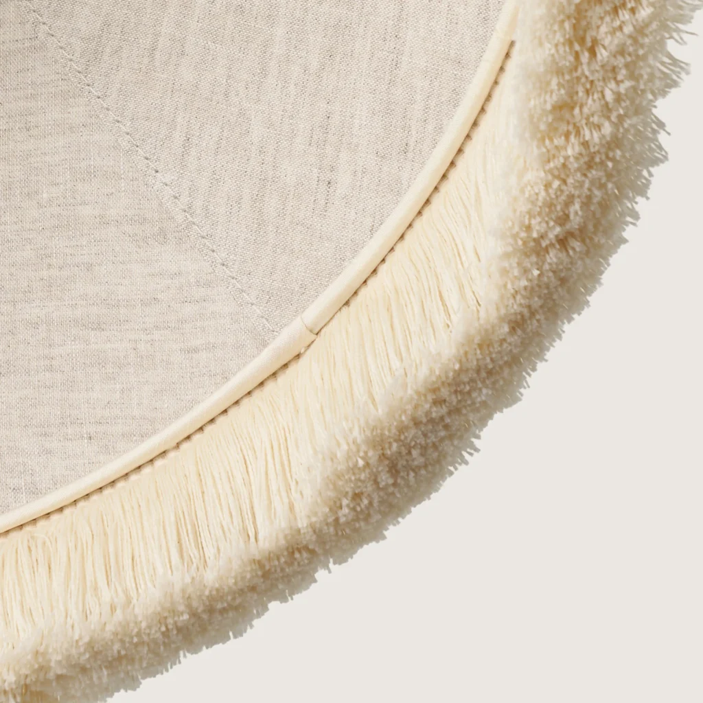 A close-up of the beautifully formed white cone-shaped lampshade, finished with a delicate white fringe along the bottom edge.