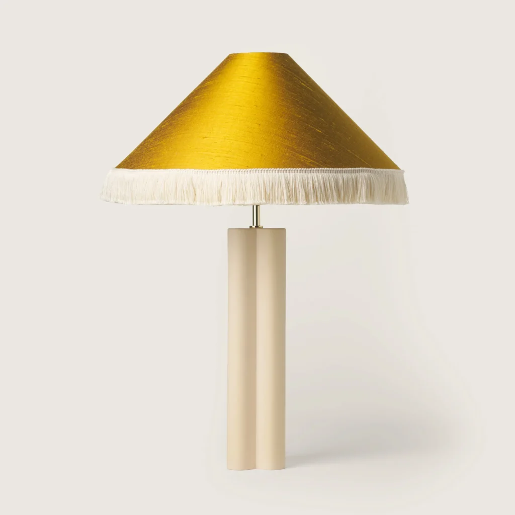 Elegant table lamp with a yellow shade, white fringe, and a cream base.