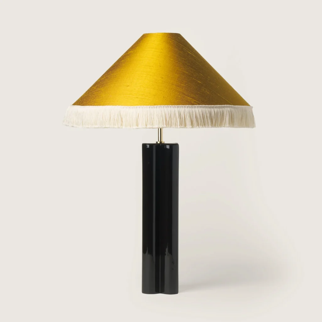 Elegant table lamp with a yellow shade, white fringe, and a black base.