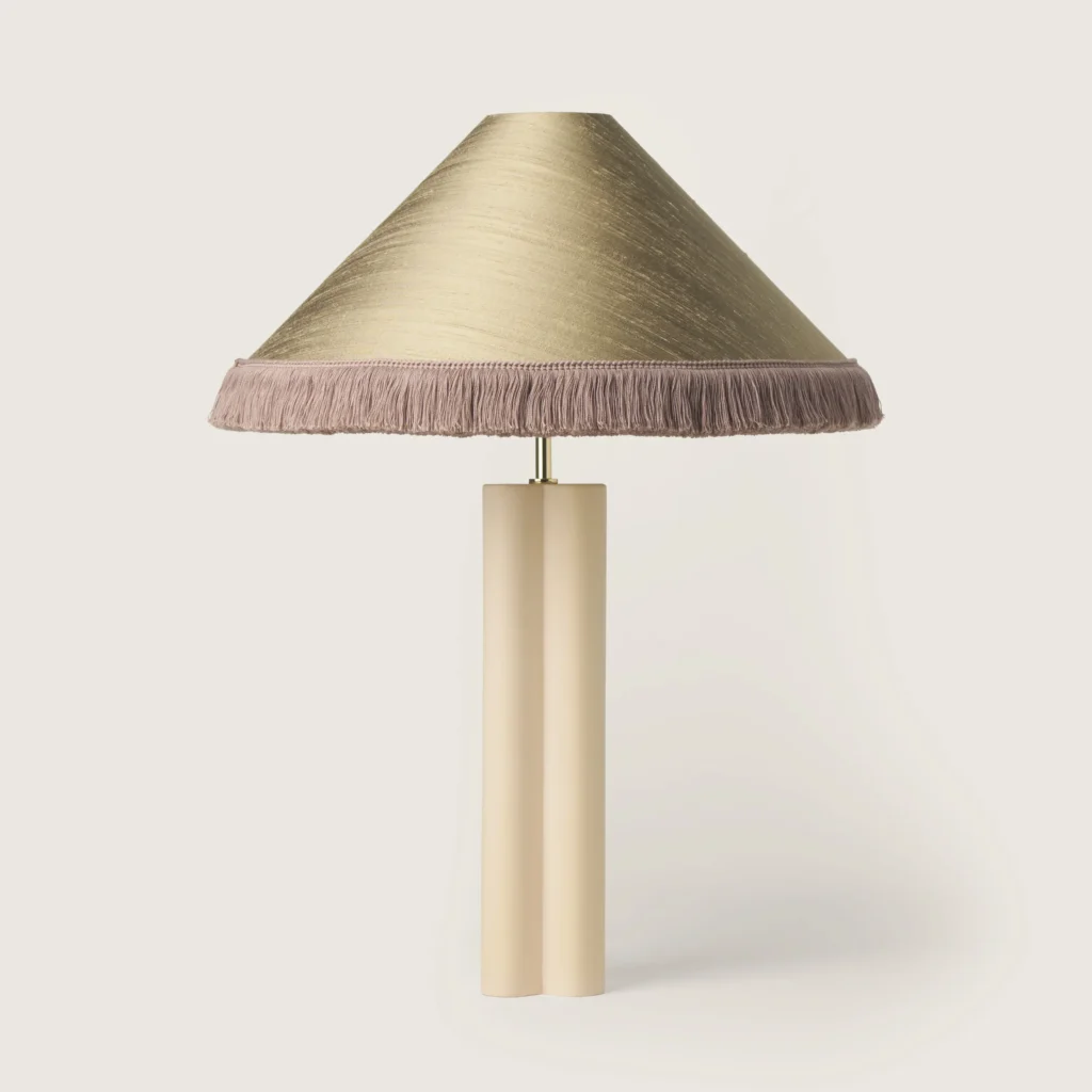 Elegant table lamp with a gray shade, gray fringe, and a cream base.