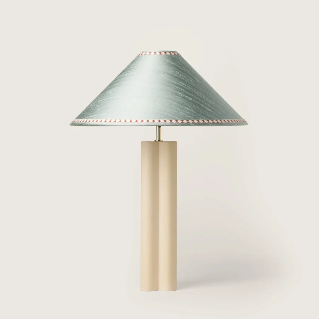 Elegant table lamp with a gray shade, ribbon, and a cream base.