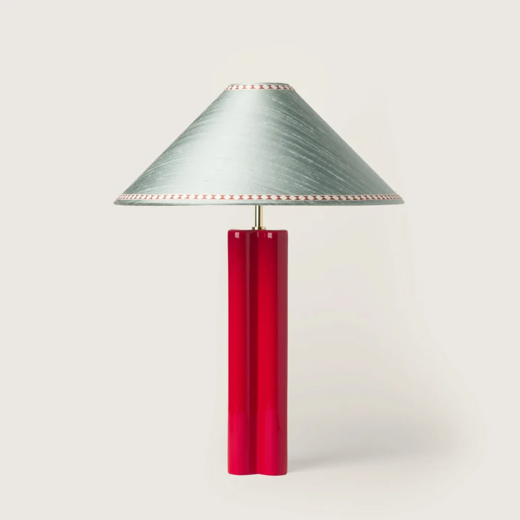 Elegant table lamp with a gray shade, ribbon, and a red base.