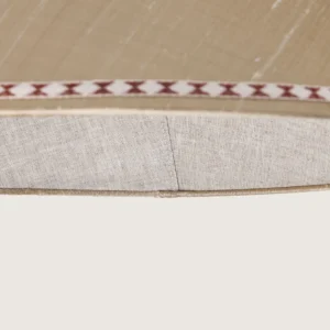 Close-up of a beautifully formed cream conical lampshade, decorated with a delicate geometric pattern along the top and bottom edges.