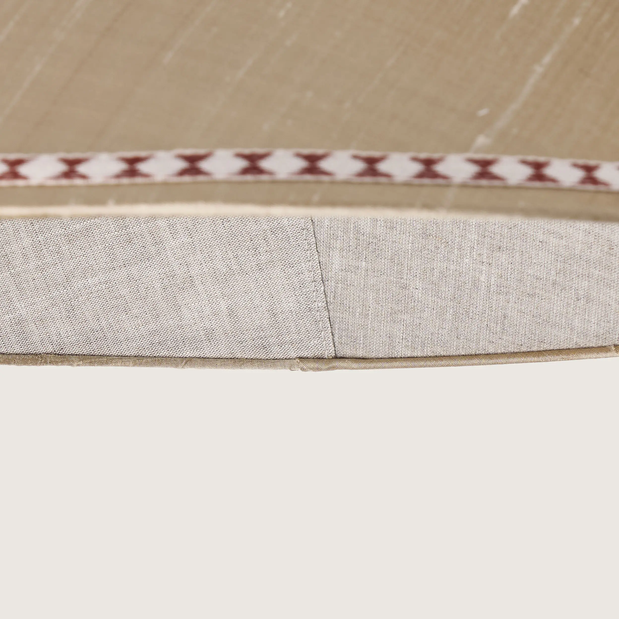 Close-up of a beautifully formed cream conical lampshade, decorated with a delicate geometric pattern along the top and bottom edges.