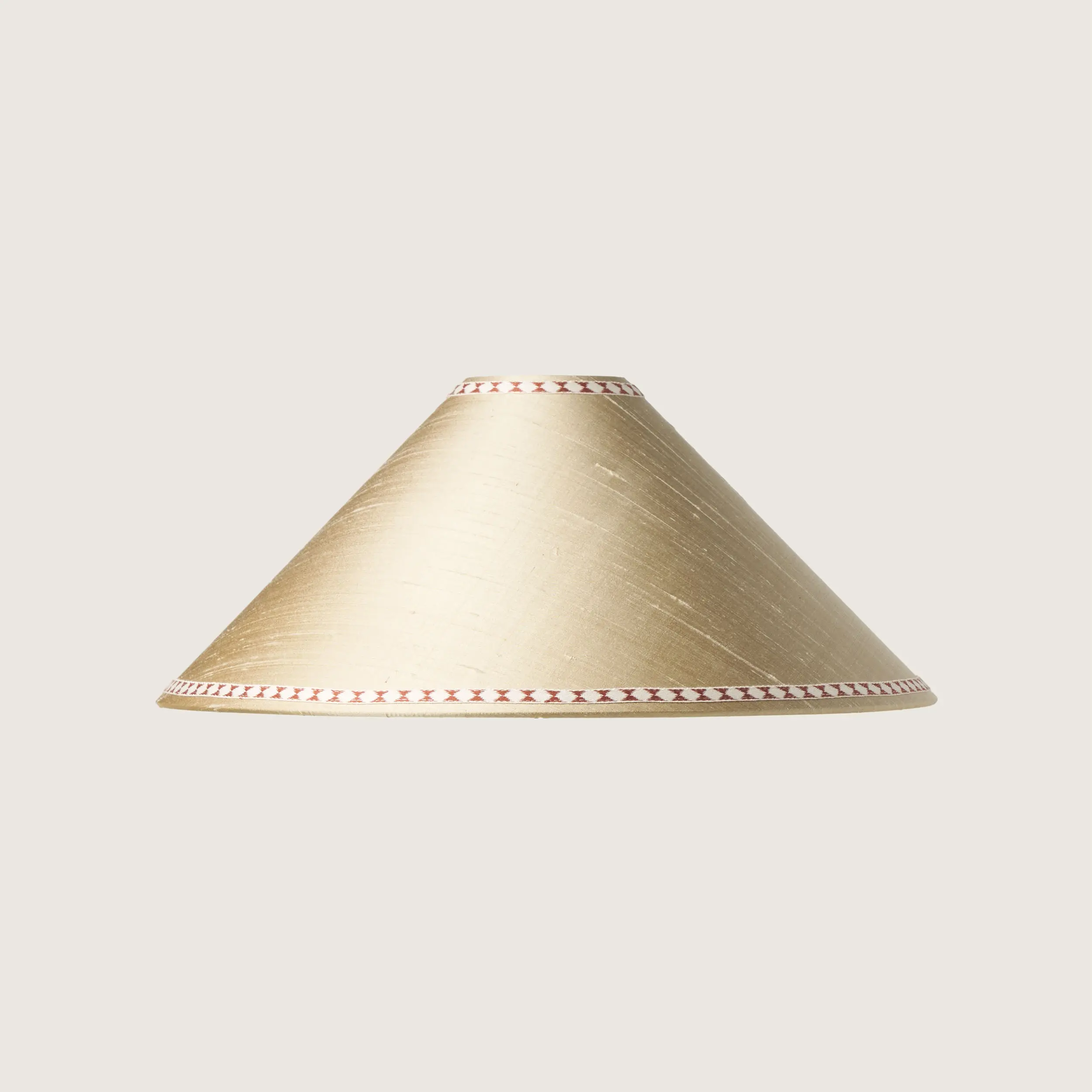 A beautifully formed cream conical lampshade, decorated with a delicate geometric pattern along the top and bottom edges.