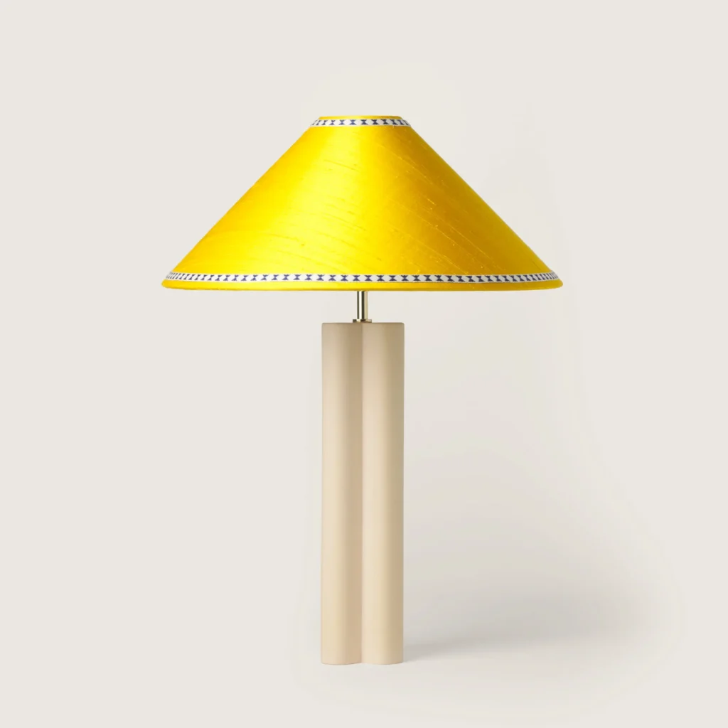 Elegant table lamp with a yellow shade, ribbon, and a cream base.