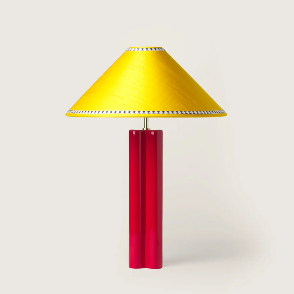 Elegant table lamp with a yellow shade, ribbon, and a red base.