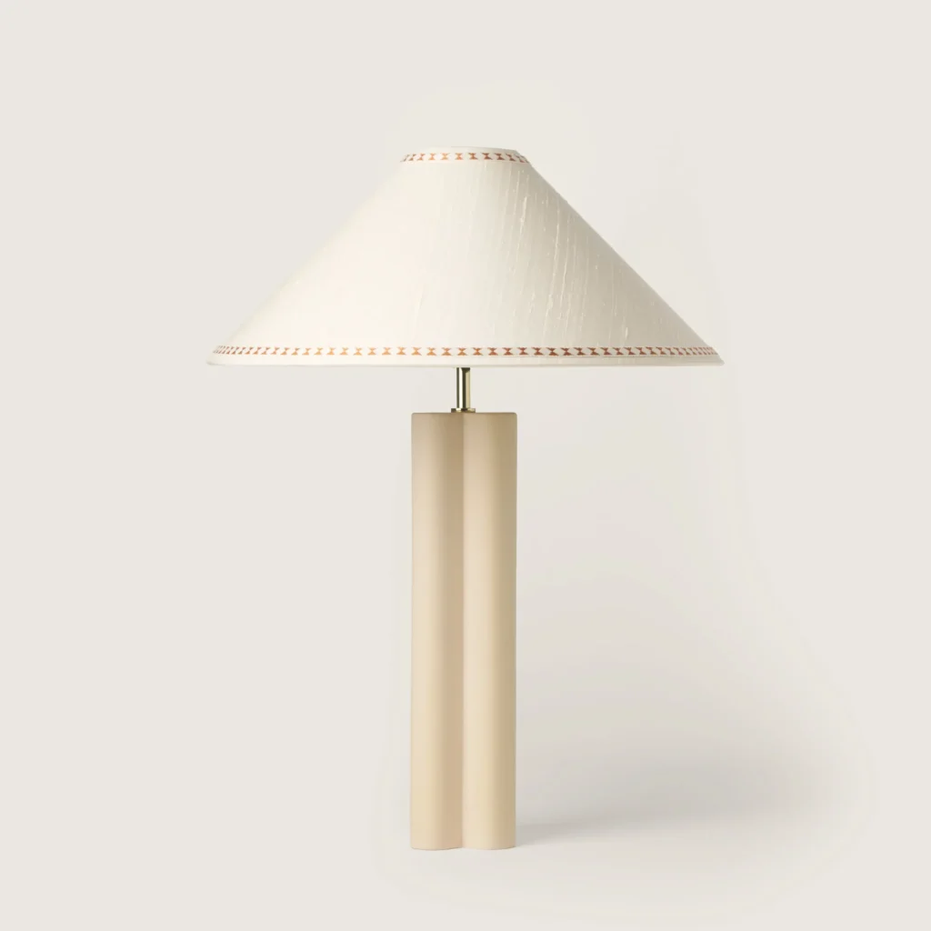 Elegant table lamp with a white shade, ribbon, and a cream base.