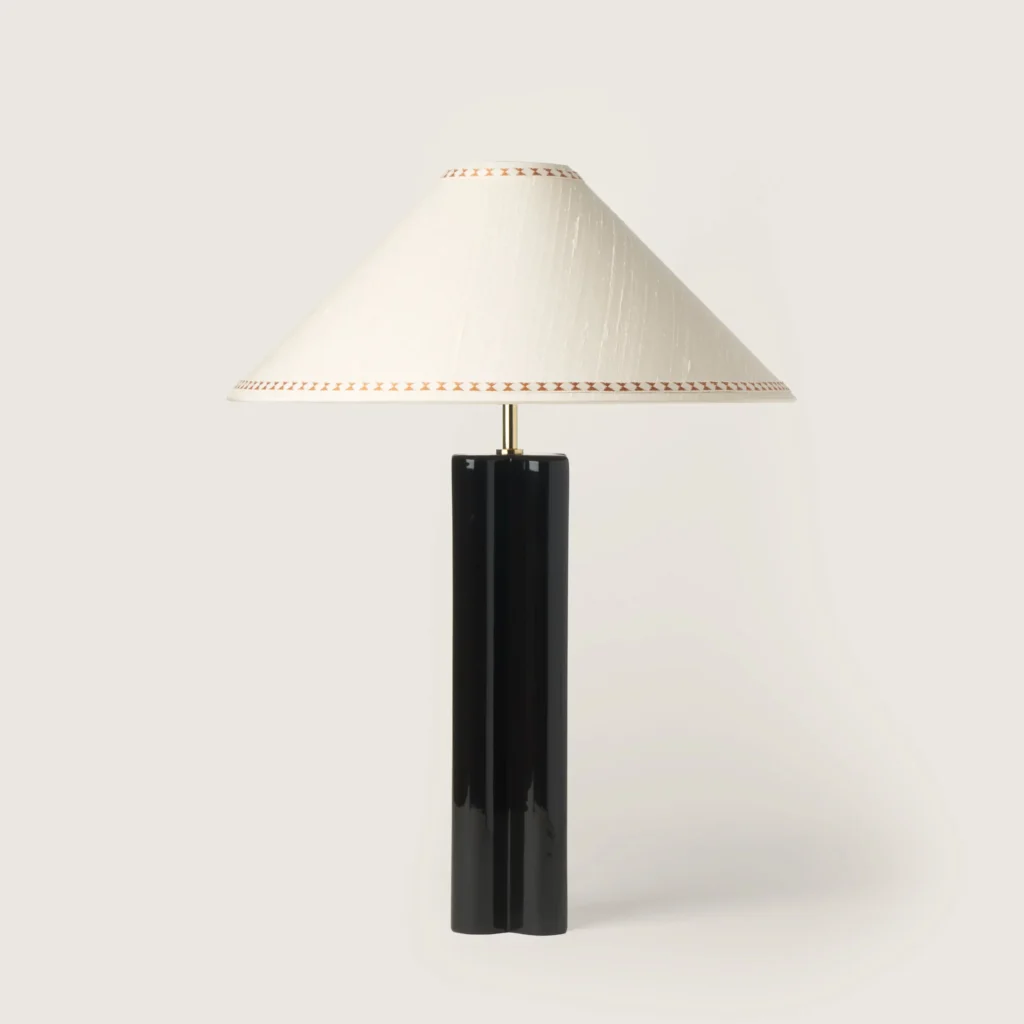 Elegant table lamp with a white shade, ribbon, and a black base.