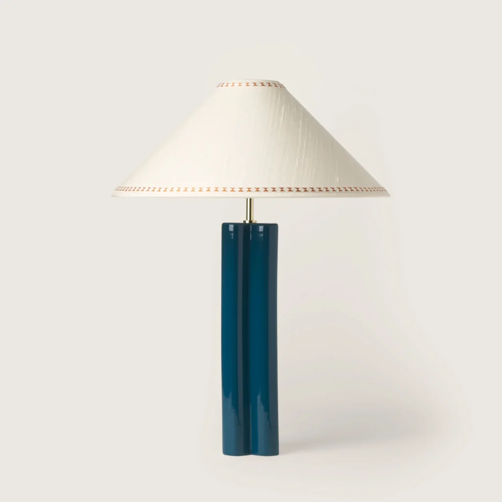 Elegant table lamp with a white shade, ribbon, and a blue base.