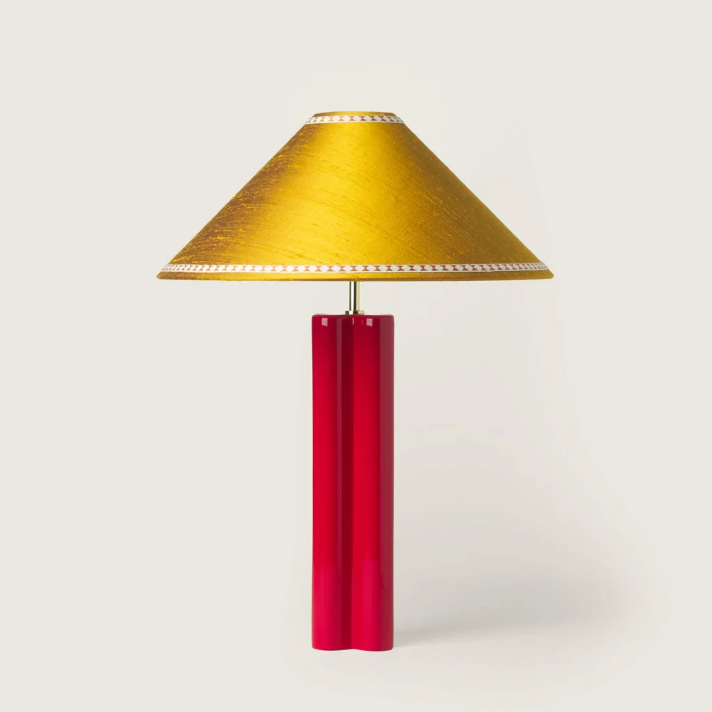 Elegant table lamp with a yellow shade, ribbon, and a red base.