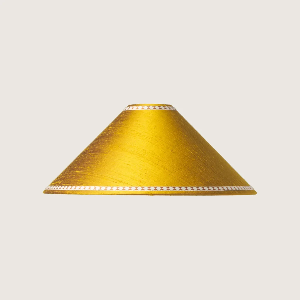 A beautifully formed yellow conical lampshade, decorated with a delicate geometric pattern along the top and bottom edges.
