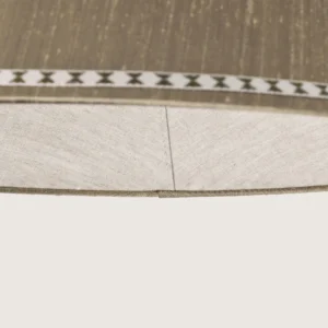 Close-up of a beautifully formed grey conical lampshade, decorated with a delicate geometric pattern along the top and bottom edges.