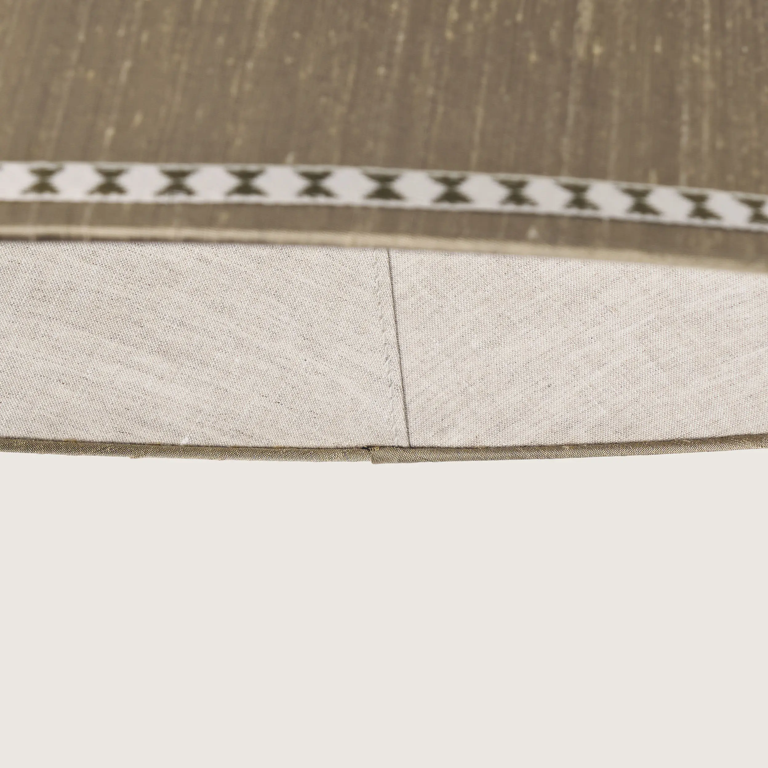 Close-up of a beautifully formed grey conical lampshade, decorated with a delicate geometric pattern along the top and bottom edges.